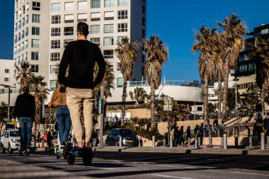 Tel Aviv, İsrail - 11 Şubat 2022 Tel Aviv sokaklarında elektrikli scooter kullanan insanlar, küçük bir iç yanmalı motorlar ve merkezde bir güverte ile çalışıyorlar.