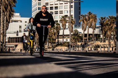 Tel Aviv, İsrail - 11 Şubat 2022 Tel Aviv sokaklarında elektrikli scooter kullanan insanlar, küçük bir iç yanmalı motorlar ve merkezde bir güverte ile çalışıyorlar.