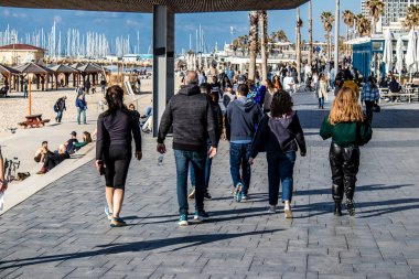 Tel Aviv, İsrail - 13 Şubat 2022 Tel Aviv Güvertesi 'nde yürüyen kimliği belirsiz insanlar, İbranice' de Tayelet olarak bilinir, İsrail 'in Tel Aviv kentindeki Akdeniz kıyısı boyunca uzanır.