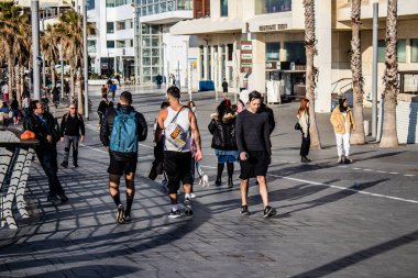 Tel Aviv, İsrail - 13 Şubat 2022 Tel Aviv Güvertesi 'nde yürüyen kimliği belirsiz insanlar, İbranice' de Tayelet olarak bilinir, İsrail 'in Tel Aviv kentindeki Akdeniz kıyısı boyunca uzanır.