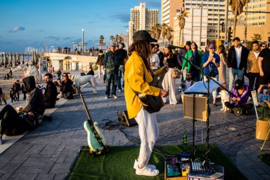 Tel Aviv, İsrail - Mart 06, 2022 Genç bağımsız şarkıcı Tel Aviv 'de denize bakan gezinti alanında bir müzik konseri veriyor, sanatçılar bu şekilde tanınıyor ve plaklarını aynı anda satıyorlar.