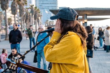 Tel Aviv, İsrail - Mart 06, 2022 Genç bağımsız şarkıcı Tel Aviv 'de denize bakan gezinti alanında bir müzik konseri veriyor, sanatçılar bu şekilde tanınıyor ve plaklarını aynı anda satıyorlar.