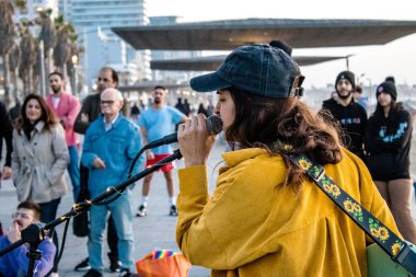 Tel Aviv, İsrail - Mart 06, 2022 Genç bağımsız şarkıcı Tel Aviv 'de denize bakan gezinti alanında bir müzik konseri veriyor, sanatçılar bu şekilde tanınıyor ve plaklarını aynı anda satıyorlar.
