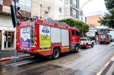 Tel Aviv, İsrail - 15 Mart 2022 İtfaiye aracı Tel Aviv sokaklarına park etmiş, itfaiyeciler şehir merkezindeki bir binanın girişindeki yangını söndürmek için müdahale etmişler.