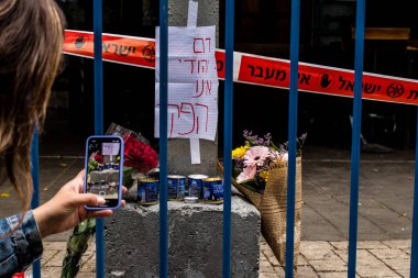Tel Aviv, İsrail - 8 Nisan 2022 Dizengoff Caddesi 'ndeki Ilka Bar' a düzenlenen terörist saldırının ardından insanlar saldırının gerçekleştiği yere mum ve çiçek bırakmak için geliyorlar.