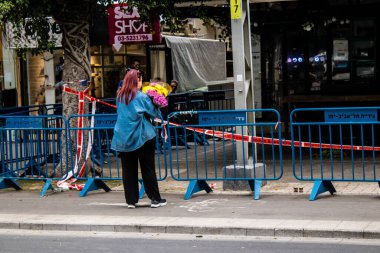 Tel Aviv, İsrail - 8 Nisan 2022 Dizengoff Caddesi 'ndeki Ilka Bar' a düzenlenen terörist saldırının ardından insanlar saldırının gerçekleştiği yere mum ve çiçek bırakmak için geliyorlar.