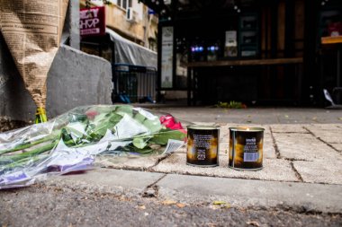 Tel Aviv, İsrail - 8 Nisan 2022 Dizengoff Caddesi 'ndeki Ilka Bar' a düzenlenen terörist saldırının ardından insanlar saldırının gerçekleştiği yere mum ve çiçek bırakmak için geliyorlar.