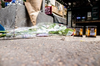 Tel Aviv, İsrail - 8 Nisan 2022 Dizengoff Caddesi 'ndeki Ilka Bar' a düzenlenen terörist saldırının ardından insanlar saldırının gerçekleştiği yere mum ve çiçek bırakmak için geliyorlar.