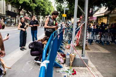 Tel Aviv, İsrail - 8 Nisan 2022 Dizengoff Caddesi 'ndeki Ilka Bar' a düzenlenen terörist saldırının ardından insanlar saldırının gerçekleştiği yere mum ve çiçek bırakmak için geliyorlar.
