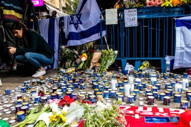 Tel Aviv, İsrail - 8 Nisan 2022 Dizengoff Caddesi 'ndeki Ilka Bar' a düzenlenen terörist saldırının ardından insanlar saldırının gerçekleştiği yere mum ve çiçek bırakmak için geliyorlar.