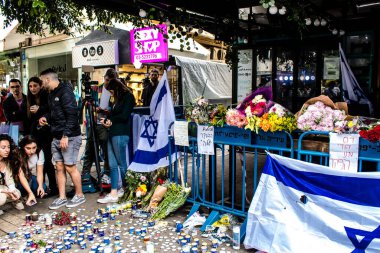 Tel Aviv, İsrail - 8 Nisan 2022 Dizengoff Caddesi 'ndeki Ilka Bar' a düzenlenen terörist saldırının ardından insanlar saldırının gerçekleştiği yere mum ve çiçek bırakmak için geliyorlar.