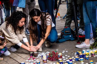 Tel Aviv, İsrail - 8 Nisan 2022 Dizengoff Caddesi 'ndeki Ilka Bar' a düzenlenen terörist saldırının ardından insanlar saldırının gerçekleştiği yere mum ve çiçek bırakmak için geliyorlar.