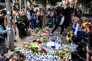 Tel Aviv, İsrail - 8 Nisan 2022 Dizengoff Caddesi 'ndeki Ilka Bar' a düzenlenen terörist saldırının ardından insanlar saldırının gerçekleştiği yere mum ve çiçek bırakmak için geliyorlar.