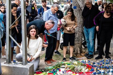 Tel Aviv, İsrail - 8 Nisan 2022 Dizengoff Caddesi 'ndeki Ilka Bar' a düzenlenen terörist saldırının ardından insanlar saldırının gerçekleştiği yere mum ve çiçek bırakmak için geliyorlar.
