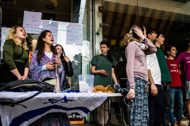 Tel Aviv, İsrail - 8 Nisan 2022 Dizengoff Caddesi 'ndeki Ilka Bar' a yapılan terörist saldırının ardından, genç İsrailli gençler saldırının gerçekleştiği yerde şarkı söylüyorlar.