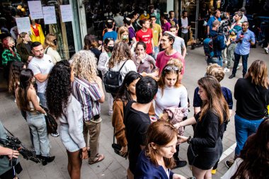 Tel Aviv, İsrail - 8 Nisan 2022 Dizengoff Caddesi 'ndeki Ilka Bar' a yapılan terörist saldırının ardından, genç İsrailli gençler saldırının gerçekleştiği yerde şarkı söylüyorlar.