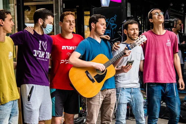 Tel Aviv, İsrail - 8 Nisan 2022 Dizengoff Caddesi 'ndeki Ilka Bar' a yapılan terörist saldırının ardından, genç İsrailli gençler saldırının gerçekleştiği yerde şarkı söylüyorlar.