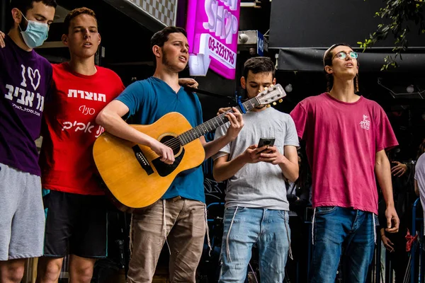 Tel Aviv, İsrail - 8 Nisan 2022 Dizengoff Caddesi 'ndeki Ilka Bar' a yapılan terörist saldırının ardından, genç İsrailli gençler saldırının gerçekleştiği yerde şarkı söylüyorlar.