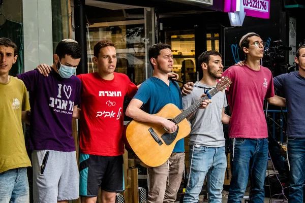 Tel Aviv, İsrail - 8 Nisan 2022 Dizengoff Caddesi 'ndeki Ilka Bar' a yapılan terörist saldırının ardından, genç İsrailli gençler saldırının gerçekleştiği yerde şarkı söylüyorlar.