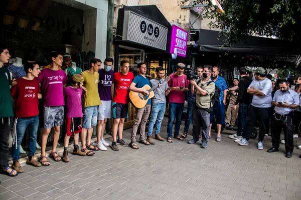 Tel Aviv, İsrail - 8 Nisan 2022 Dizengoff Caddesi 'ndeki Ilka Bar' a yapılan terörist saldırının ardından, genç İsrailli gençler saldırının gerçekleştiği yerde şarkı söylüyorlar.