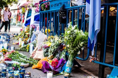 Tel Aviv, İsrail - 10 Nisan 2022 Dizengoff Caddesi 'ndeki Ilka Bar' a düzenlenen terörist saldırının ardından insanlar saldırının gerçekleştiği yere mum ve çiçek bırakmak için geliyorlar.