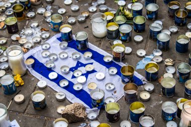 Tel Aviv, İsrail - 10 Nisan 2022 Dizengoff Caddesi 'ndeki Ilka Bar' a düzenlenen terörist saldırının ardından insanlar saldırının gerçekleştiği yere mum ve çiçek bırakmak için geliyorlar.