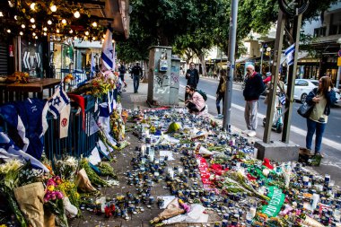 Tel Aviv, İsrail - 10 Nisan 2022 Dizengoff Caddesi 'ndeki Ilka Bar' a düzenlenen terörist saldırının ardından insanlar saldırının gerçekleştiği yere mum ve çiçek bırakmak için geliyorlar.