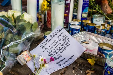 Tel Aviv, İsrail - 10 Nisan 2022 Dizengoff Caddesi 'ndeki Ilka Bar' a düzenlenen terörist saldırının ardından insanlar saldırının gerçekleştiği yere mum ve çiçek bırakmak için geliyorlar.
