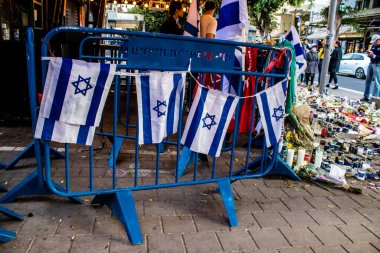 Tel Aviv, İsrail - 10 Nisan 2022 Dizengoff Caddesi 'ndeki Ilka Bar' a düzenlenen terörist saldırının ardından insanlar saldırının gerçekleştiği yere mum ve çiçek bırakmak için geliyorlar.