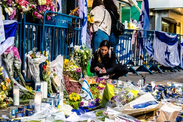 Tel Aviv, İsrail - 10 Nisan 2022 Dizengoff Caddesi 'ndeki Ilka Bar' a düzenlenen terörist saldırının ardından insanlar saldırının gerçekleştiği yere mum ve çiçek bırakmak için geliyorlar.