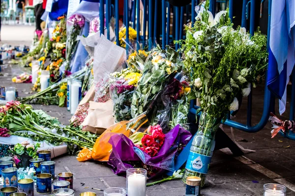 Tel Aviv, İsrail - 10 Nisan 2022 Dizengoff Caddesi 'ndeki Ilka Bar' a düzenlenen terörist saldırının ardından insanlar saldırının gerçekleştiği yere mum ve çiçek bırakmak için geliyorlar.