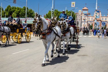 Seville, İspanya - 1 Mayıs 2022 Sevillianlar geleneksel Endülüs tarzında giyinmiş bir at arabasıyla İspanya 'nın en ünlü festivali olan Feria de Sevilla' nın koridorlarında dolaşıyorlar.