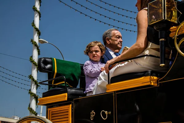 Seville, İspanya - 1 Mayıs 2022 Sevillianlar geleneksel Endülüs tarzında giyinmiş bir at arabasıyla İspanya 'nın en ünlü festivali olan Feria de Sevilla' nın koridorlarında dolaşıyorlar.