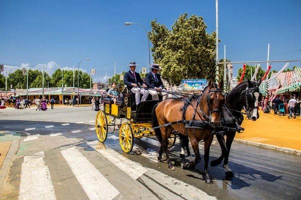 Seville, İspanya - 1 Mayıs 2022 Sevillianlar geleneksel Endülüs tarzında giyinmiş bir at arabasıyla İspanya 'nın en ünlü festivali olan Feria de Sevilla' nın koridorlarında dolaşıyorlar.