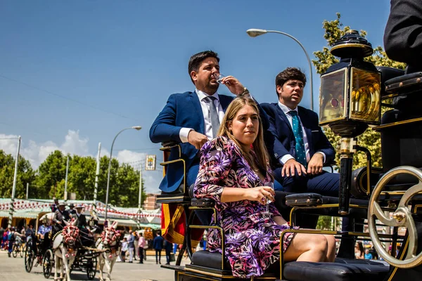 Seville, İspanya - 1 Mayıs 2022 Sevillianlar geleneksel Endülüs tarzında giyinmiş bir at arabasıyla İspanya 'nın en ünlü festivali olan Feria de Sevilla' nın koridorlarında dolaşıyorlar.