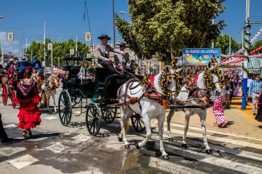 Seville, İspanya - 1 Mayıs 2022 Sevillianlar geleneksel Endülüs tarzında giyinmiş bir at arabasıyla İspanya 'nın en ünlü festivali olan Feria de Sevilla' nın koridorlarında dolaşıyorlar.