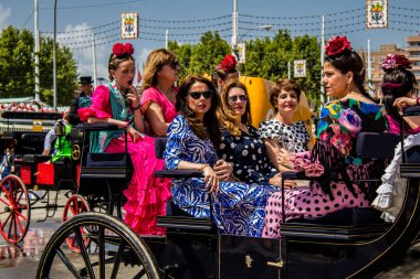 Seville, Spain - May 01, 2022 Sevillians dressed in the traditional Andalusian way riding in a horse drawn carriage through the aisles of the Feria de Sevilla, the most famous festival in Spain