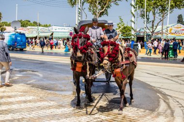 Seville, İspanya - 1 Mayıs 2022 Sevillianlar geleneksel Endülüs tarzında giyinmiş bir at arabasıyla İspanya 'nın en ünlü festivali olan Feria de Sevilla' nın koridorlarında dolaşıyorlar.