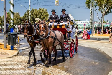 Seville, İspanya - 1 Mayıs 2022 Sevillianlar geleneksel Endülüs tarzında giyinmiş bir at arabasıyla İspanya 'nın en ünlü festivali olan Feria de Sevilla' nın koridorlarında dolaşıyorlar.