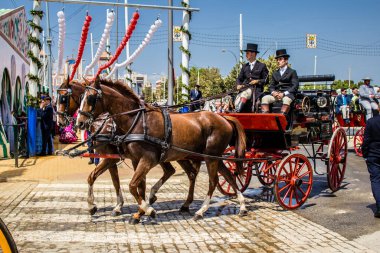 Seville, İspanya - 1 Mayıs 2022 Sevillianlar geleneksel Endülüs tarzında giyinmiş bir at arabasıyla İspanya 'nın en ünlü festivali olan Feria de Sevilla' nın koridorlarında dolaşıyorlar.