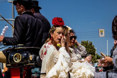 Seville, İspanya - 1 Mayıs 2022 Sevillianlar geleneksel Endülüs tarzında giyinmiş bir at arabasıyla İspanya 'nın en ünlü festivali olan Feria de Sevilla' nın koridorlarında dolaşıyorlar.