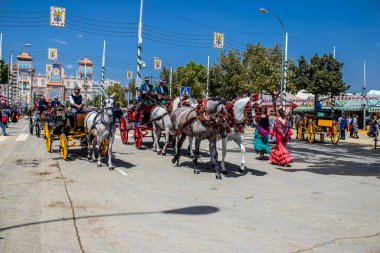 Seville, İspanya - 1 Mayıs 2022 Sevillianlar geleneksel Endülüs tarzında giyinmiş bir at arabasıyla İspanya 'nın en ünlü festivali olan Feria de Sevilla' nın koridorlarında dolaşıyorlar.
