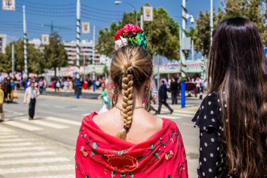 Seville, İspanya - 1 Mayıs 2022 Sevillianlar geleneksel Endülüs tarzında giyinmiş bir at arabasıyla İspanya 'nın en ünlü festivali olan Feria de Sevilla' nın koridorlarında dolaşıyorlar.