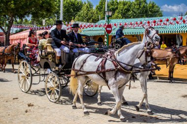 Seville, İspanya - 1 Mayıs 2022 Sevillianlar geleneksel Endülüs tarzında giyinmiş bir at arabasıyla İspanya 'nın en ünlü festivali olan Feria de Sevilla' nın koridorlarında dolaşıyorlar.