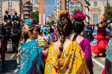 Seville, İspanya - 1 Mayıs 2022 Sevillianlar geleneksel Endülüs tarzında giyinmiş bir at arabasıyla İspanya 'nın en ünlü festivali olan Feria de Sevilla' nın koridorlarında dolaşıyorlar.