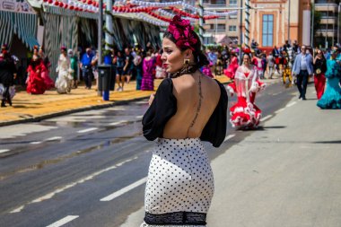 Seville, İspanya - 1 Mayıs 2022 Sevillianlar geleneksel Endülüs tarzında giyinmiş bir at arabasıyla İspanya 'nın en ünlü festivali olan Feria de Sevilla' nın koridorlarında dolaşıyorlar.