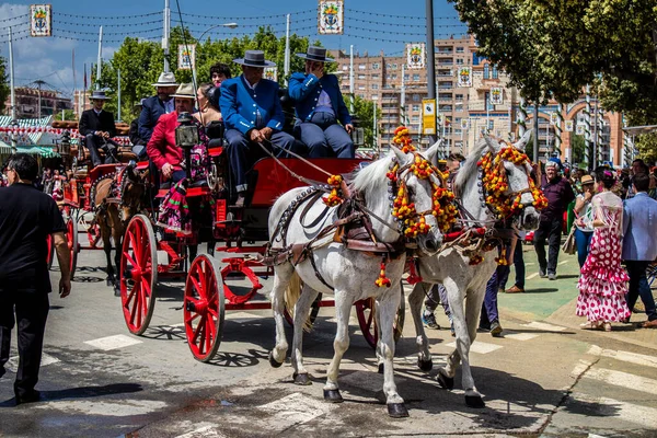 Seville, İspanya - 1 Mayıs 2022 Sevillianlar geleneksel Endülüs tarzında giyinmiş bir at arabasıyla İspanya 'nın en ünlü festivali olan Feria de Sevilla' nın koridorlarında dolaşıyorlar.