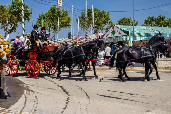 Seville, İspanya - 1 Mayıs 2022 Sevillianlar geleneksel Endülüs tarzında giyinmiş bir at arabasıyla İspanya 'nın en ünlü festivali olan Feria de Sevilla' nın koridorlarında dolaşıyorlar.