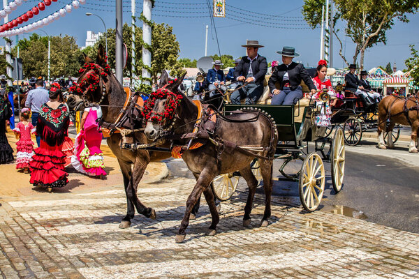 Севилья, Испания - 01 мая 2022 года Севилья, одетые в традиционный андалузский стиль верховой езды в конном экипаже через проходы Feria de Sevilla, самый известный фестиваль в Испании