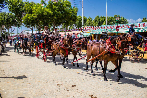 Севилья, Испания - 01 мая 2022 года Севилья, одетые в традиционный андалузский стиль верховой езды в конном экипаже через проходы Feria de Sevilla, самый известный фестиваль в Испании